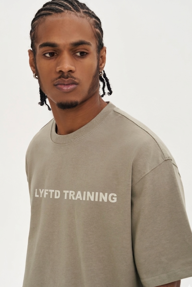 Man wearing a beige t-shirt with 'LYFTD TRAINING' text on a white background